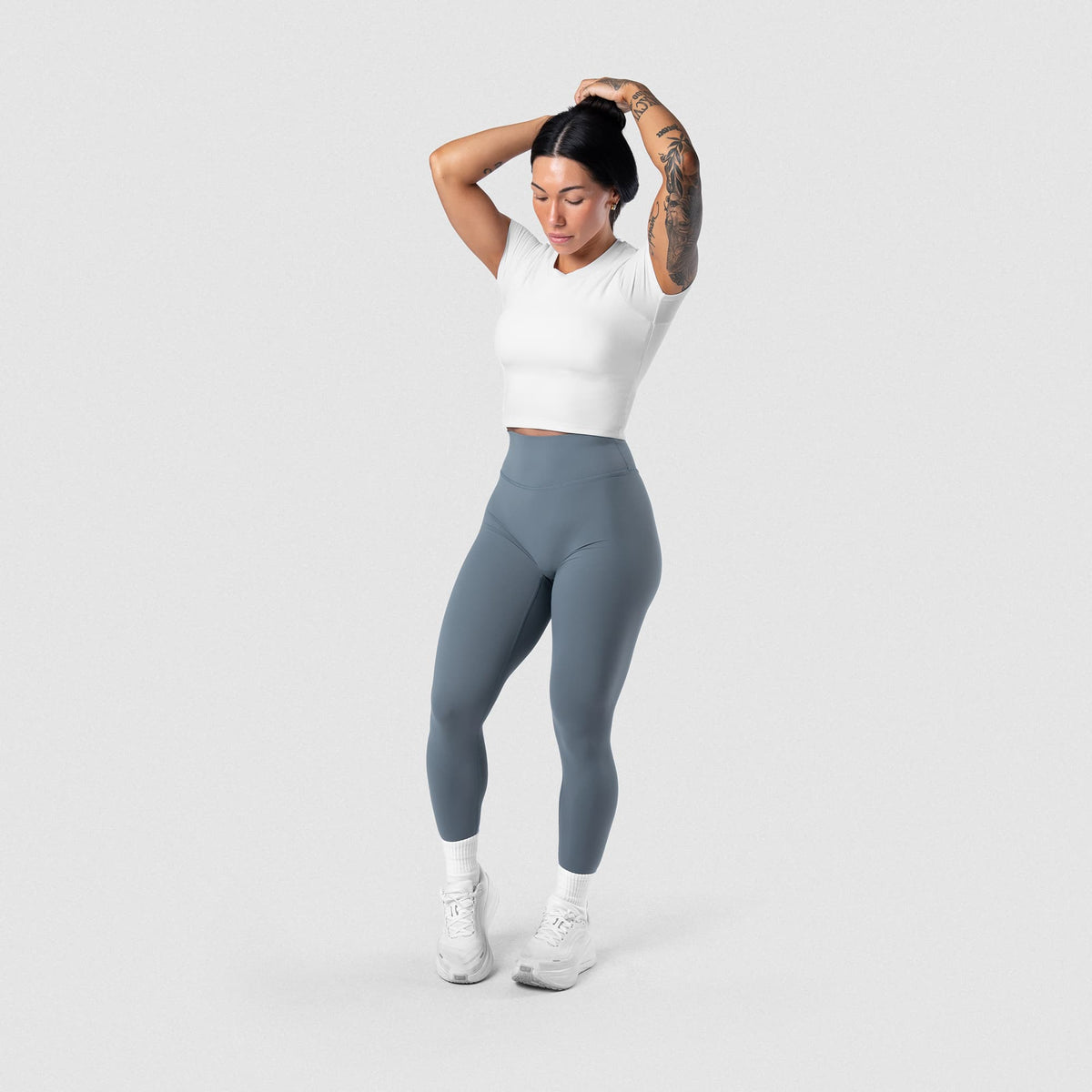 Female model wearing the Axis Support Baby Tee - White full-body view
