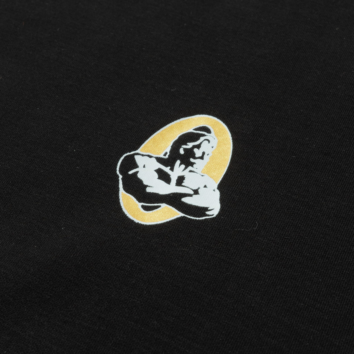Close up of small embroidered graphic logo on the Champions Gold Full Length Training Tee for the Olympia Champions Gold bodybuilding championship