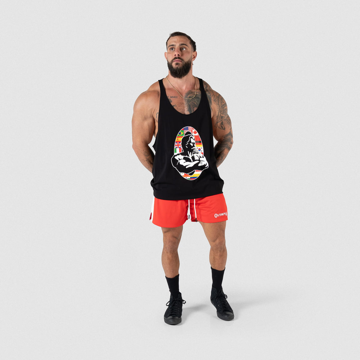 Male Model wearing the Olympia International Division Stringer tank top with red shorts