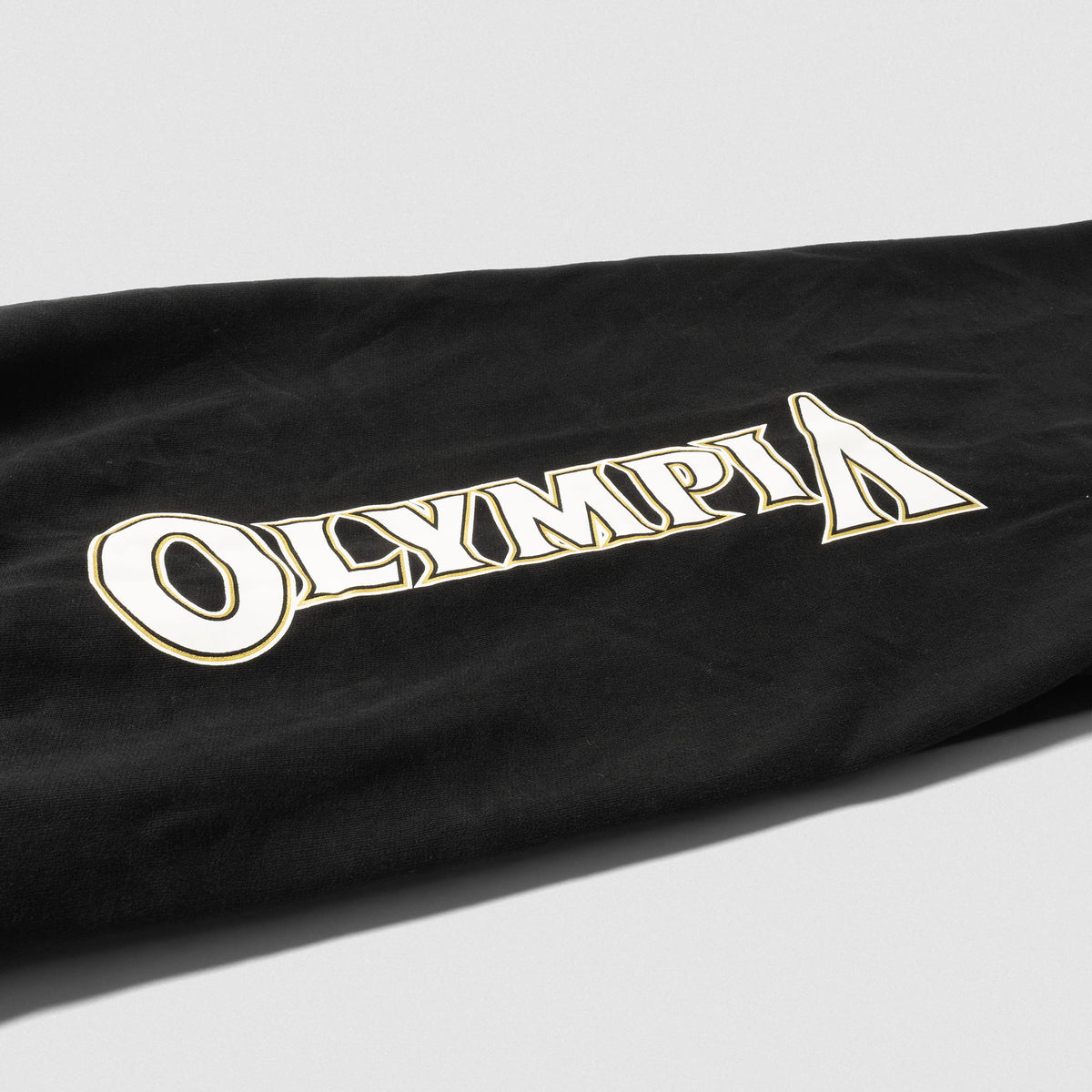 Close up of "OLYMPIA" wordmark logo found down the pantleg of the women's Champions Gold Wide-Leg Jogger