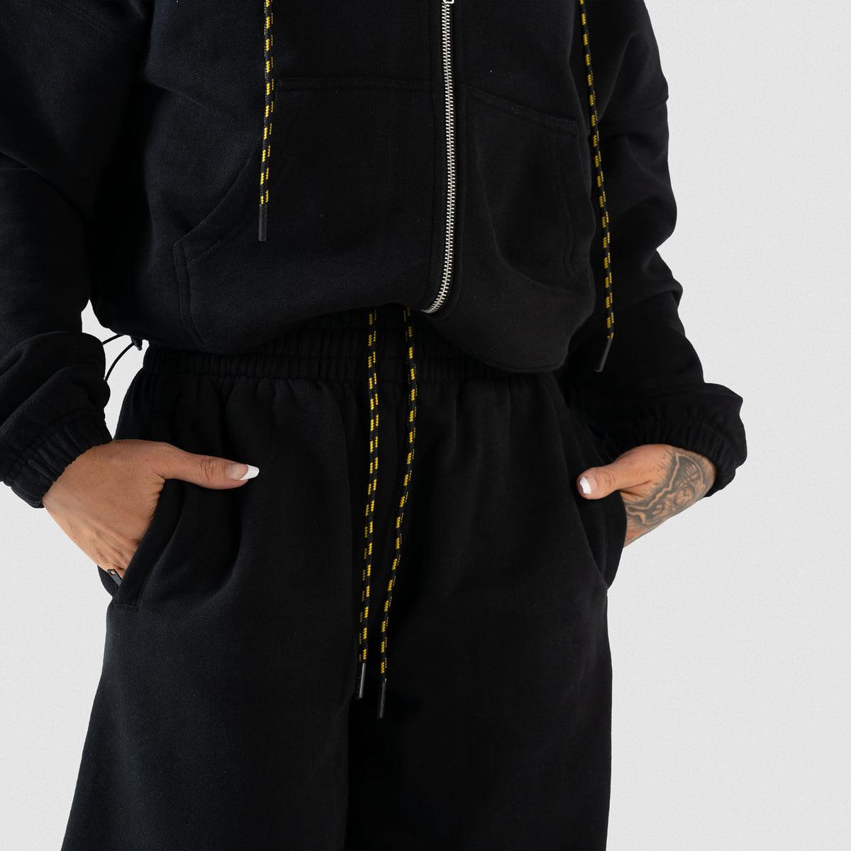 Close up of the Champions Gold Wide-Leg Jogger in black, with a model inserting hands in the two side pockets
