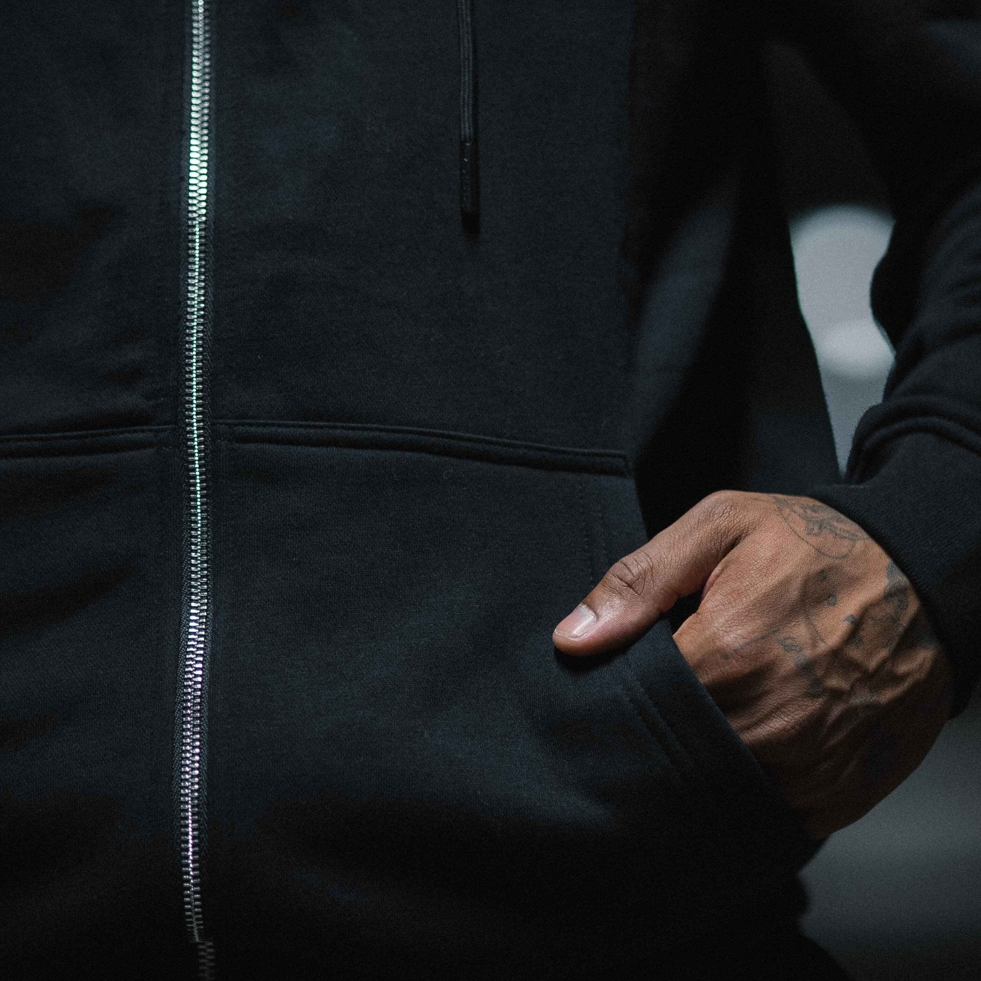 axis zip up black white with hand in front pocket close up