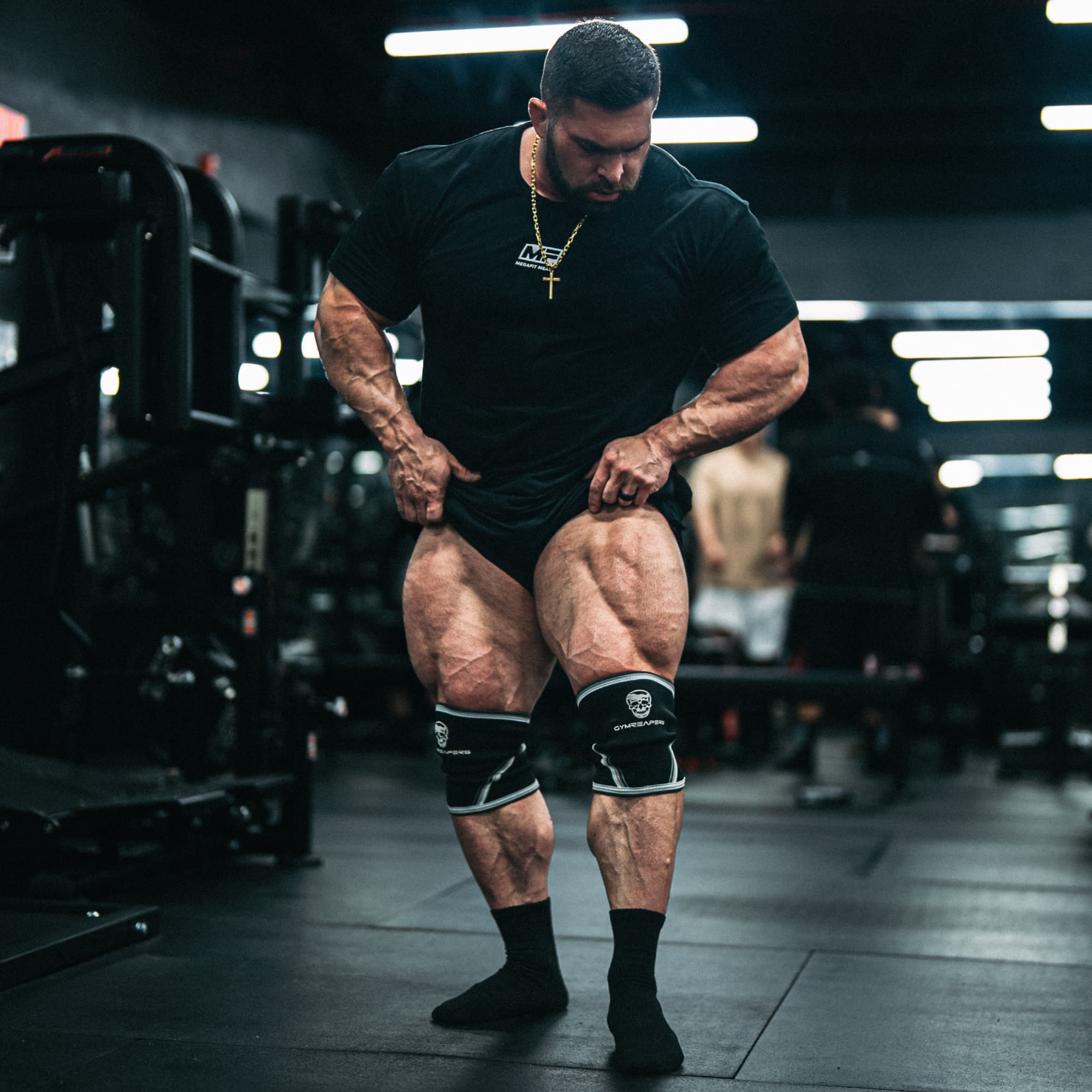 Athlete flexing quads while wearing black/white 7mm knee sleeves