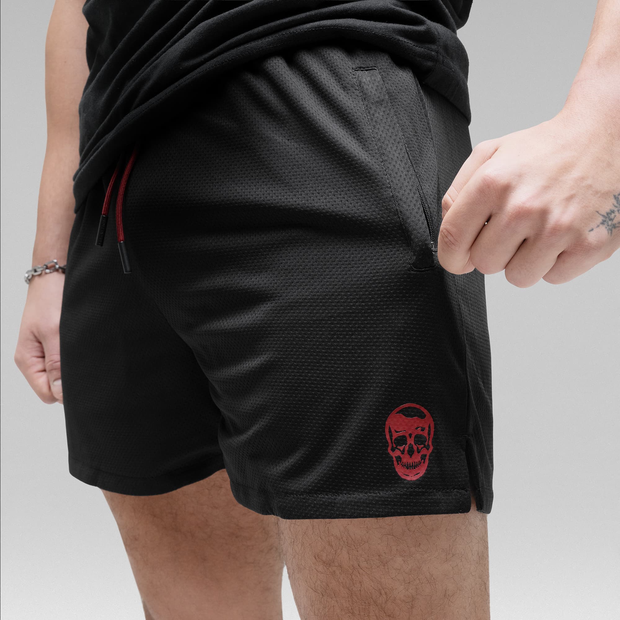 Athlete wearing the Black/Red Core Skull Mesh Training Shorts detail shot of zipper and logo