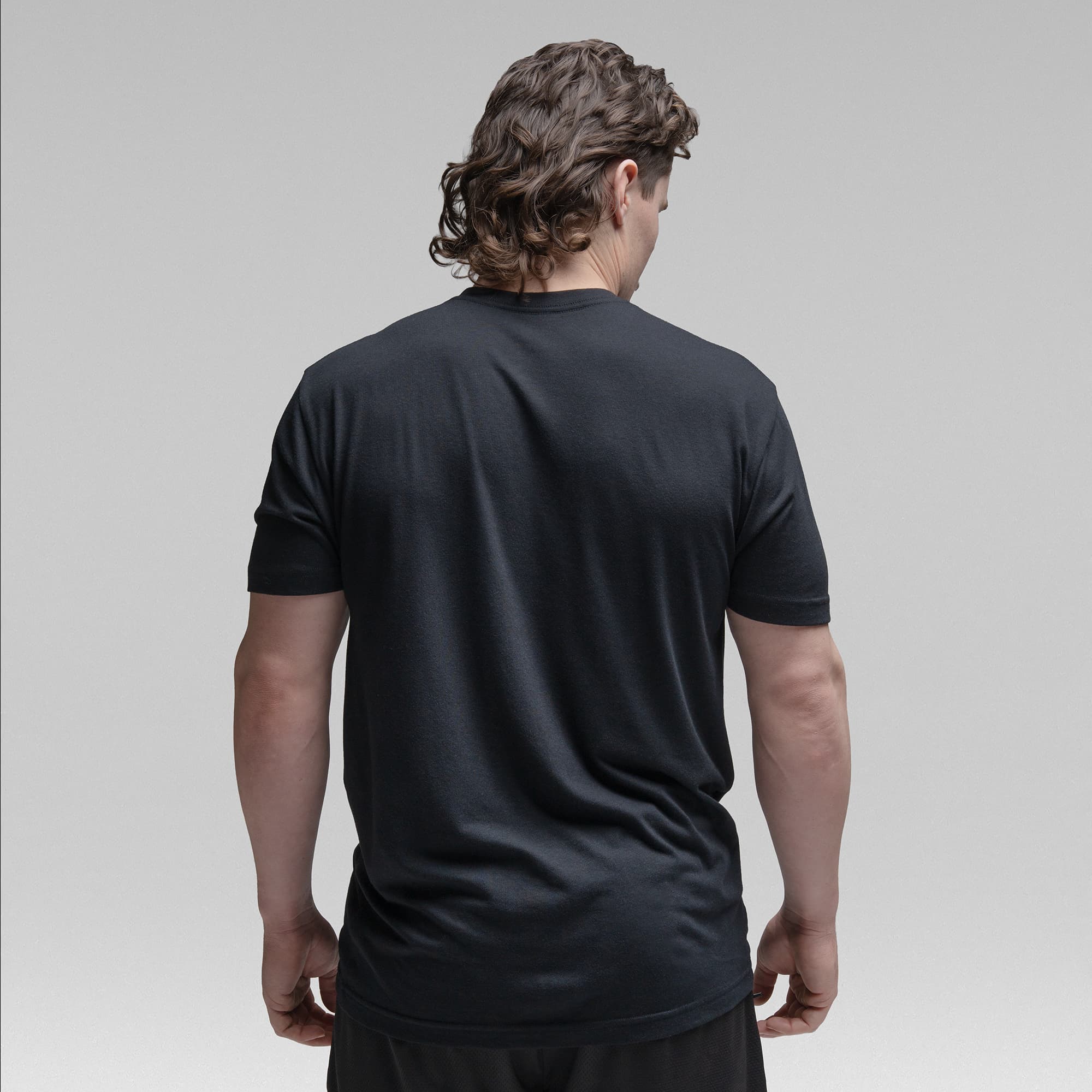 Athlete wearing the black tri blend tee half body shot back view