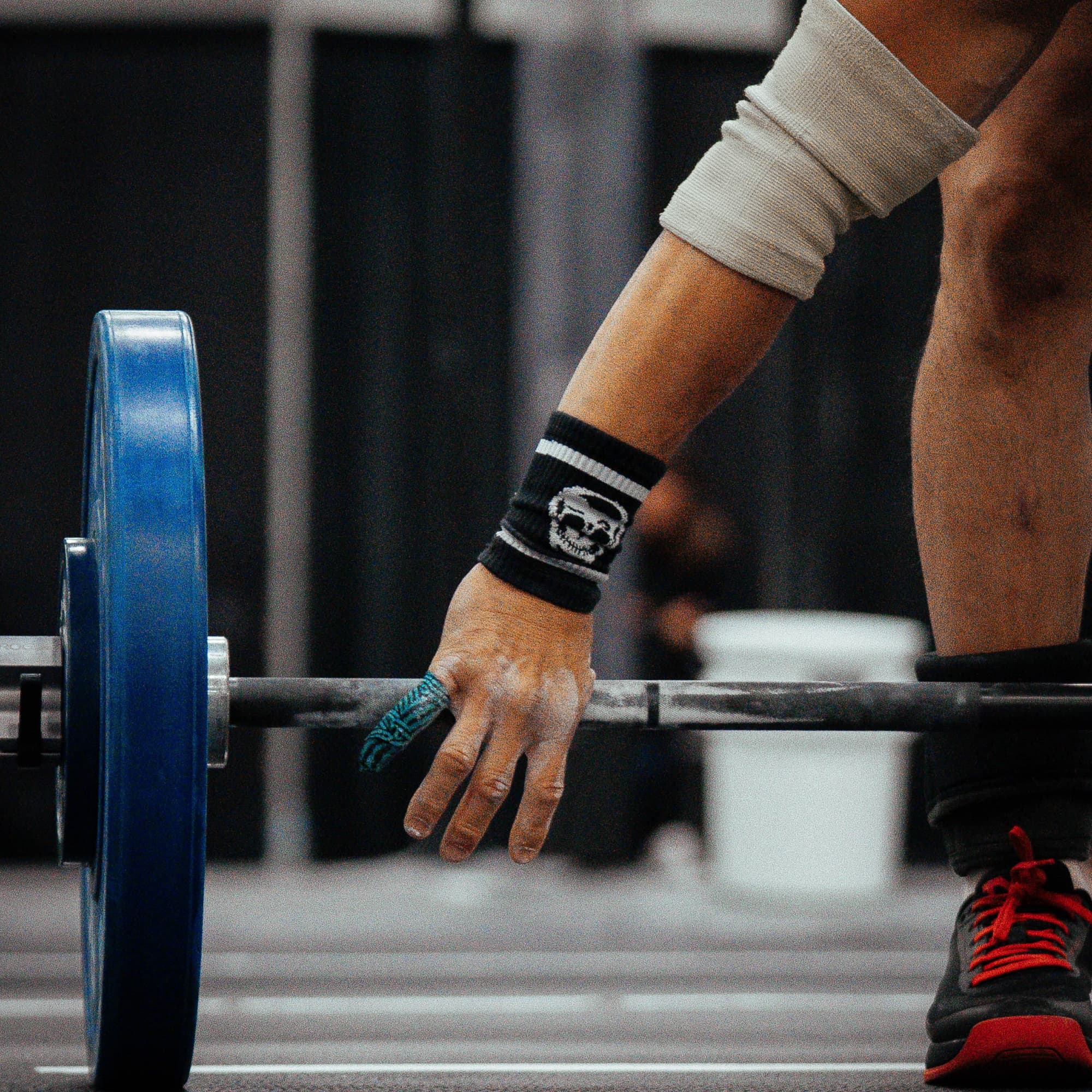 athlete grabbing barbell with skull wrist bands on