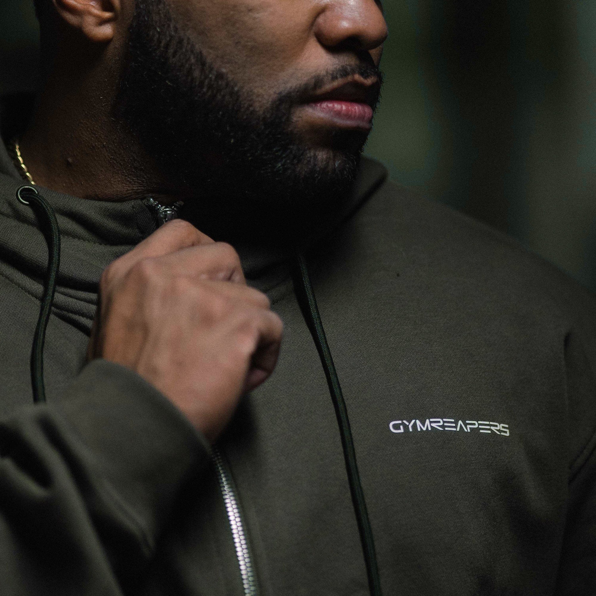 axis zip up od green athlete holding front zipper.