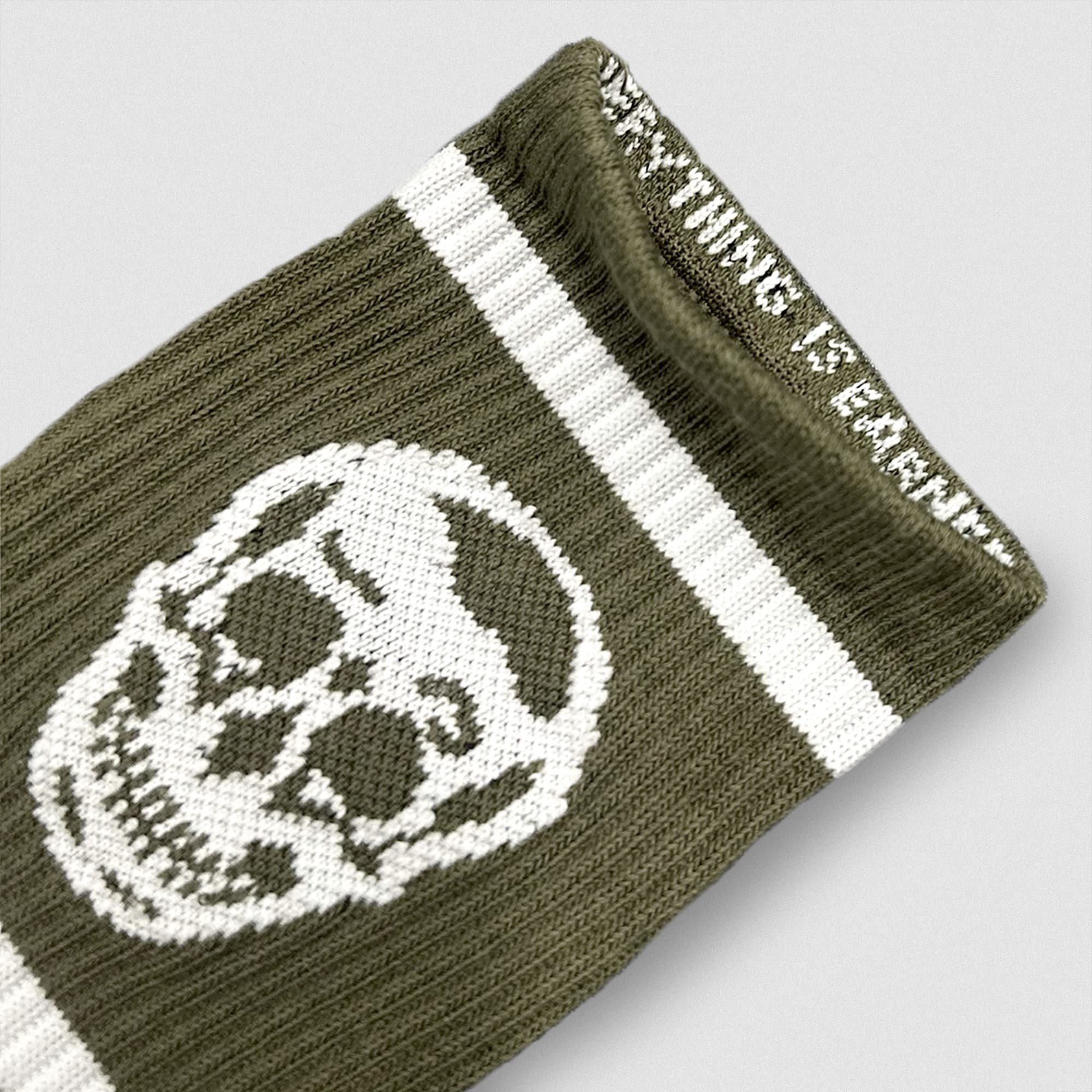 Close-up of a green Gymreapers wristband featuring a white skull design and woven mantra along the inner cuff.