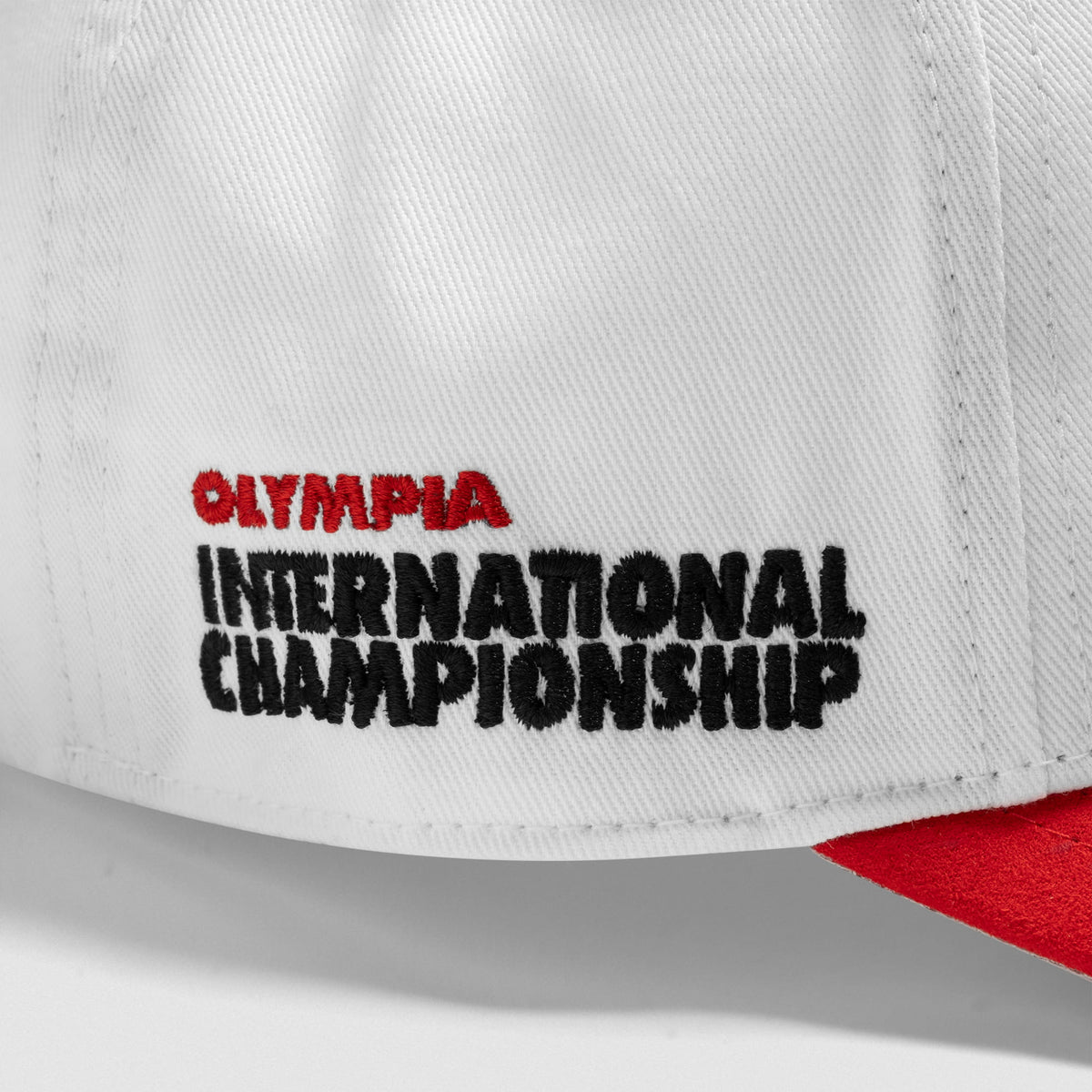 The side wordmark of the International Division Suede 5-Panel Hat that says Olympia International Championship in Black stitching 