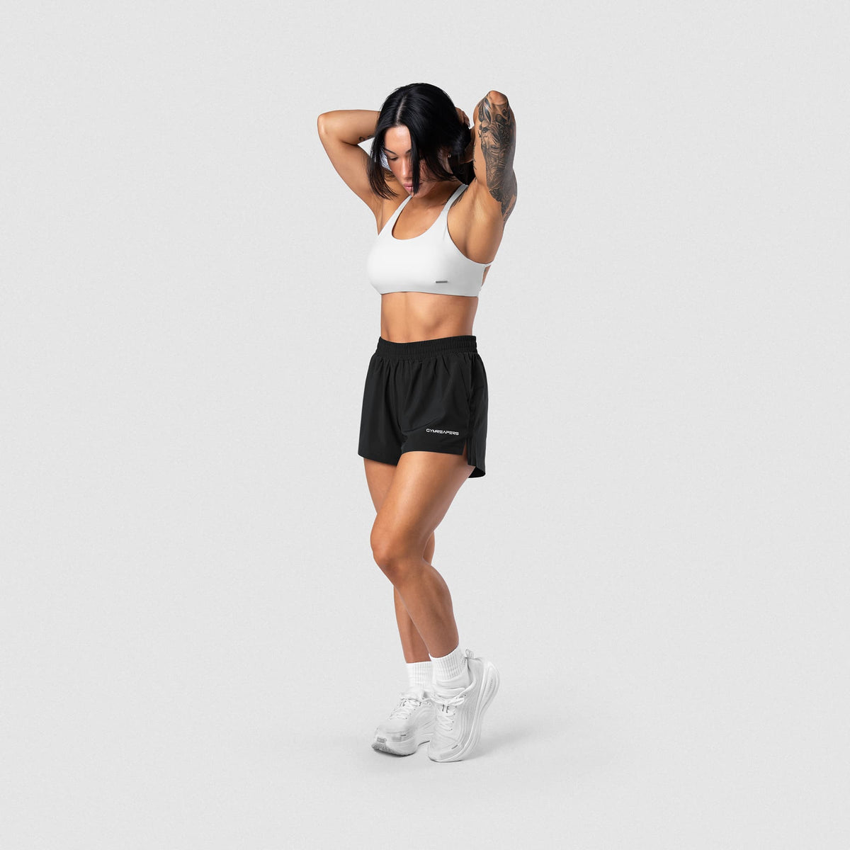 Female model wearing the Axis Open Back Bra - White full-body side view