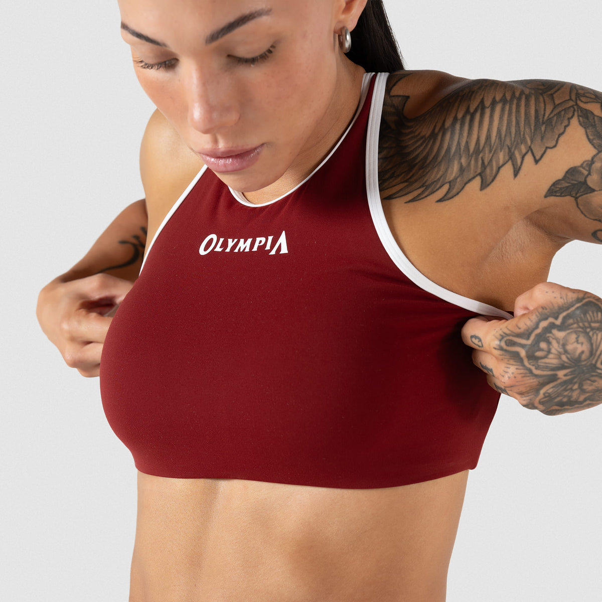 Female model adjusting the Red and White High neck Olympia sports bra