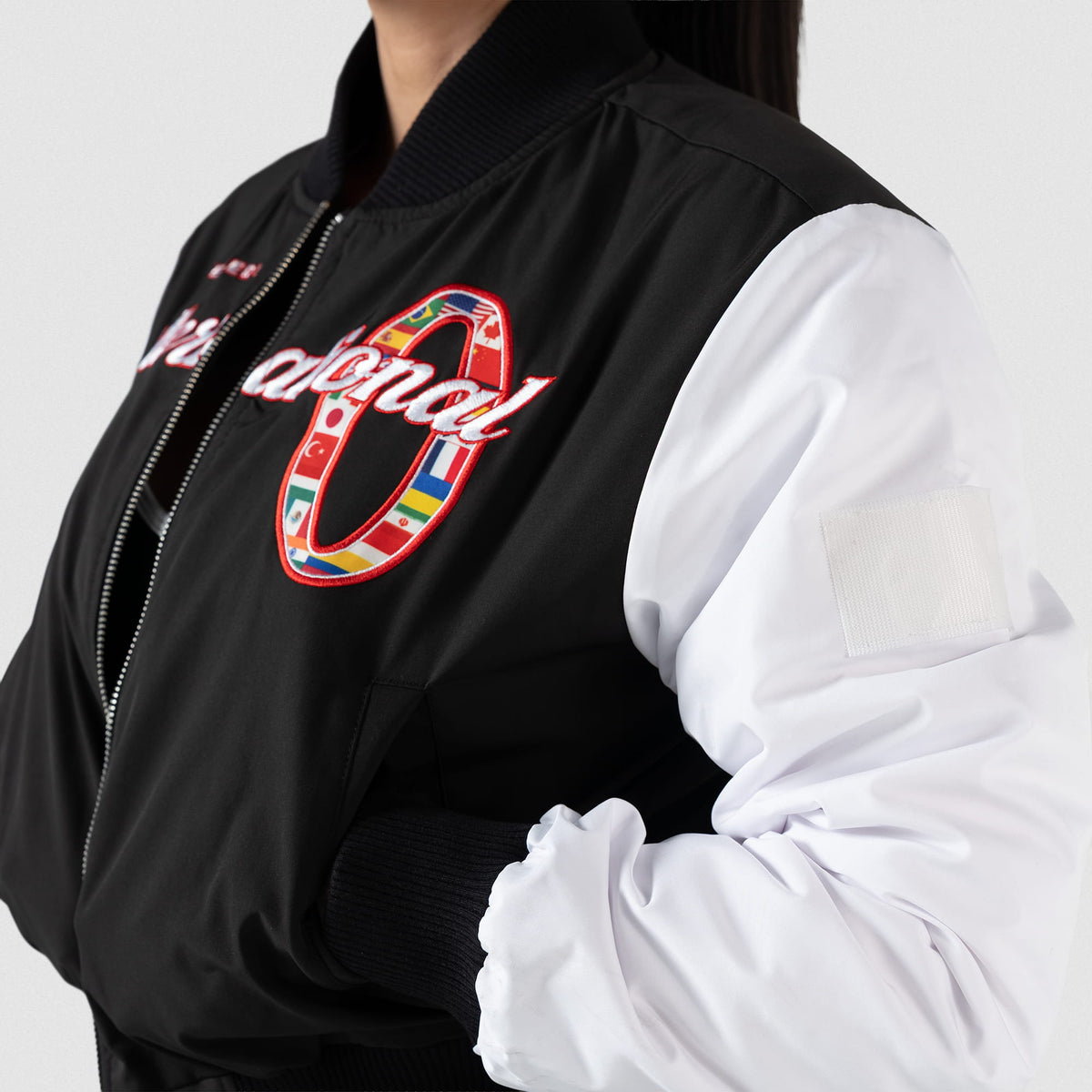 International Division Crop Bomber Jacket | Side view of model wearing the jacket with hands in pockets