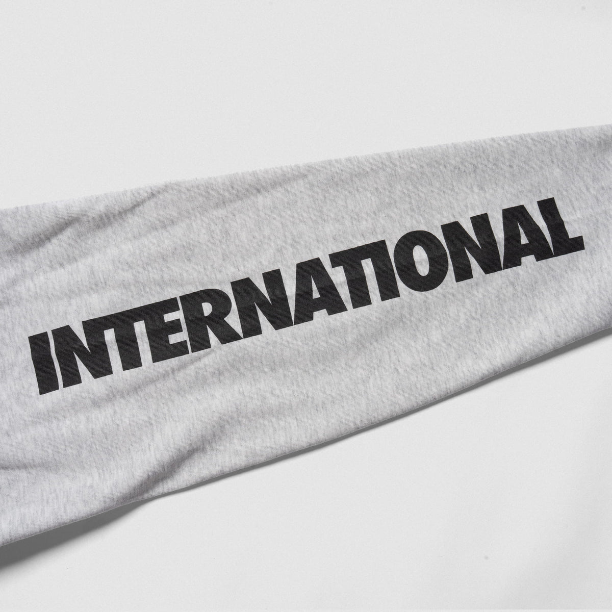 Close up view of the "International" wordmark logo down the right sleeve of the Olympia International Division Crop Long Sleeve