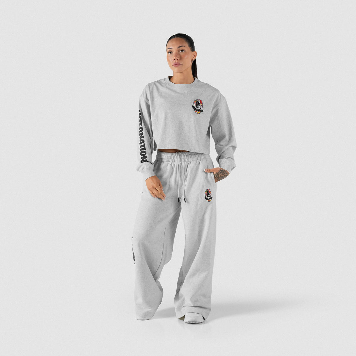 Full body view of female model wearing the Olympia International Division Crop Long Sleeve with the matching sweatpants