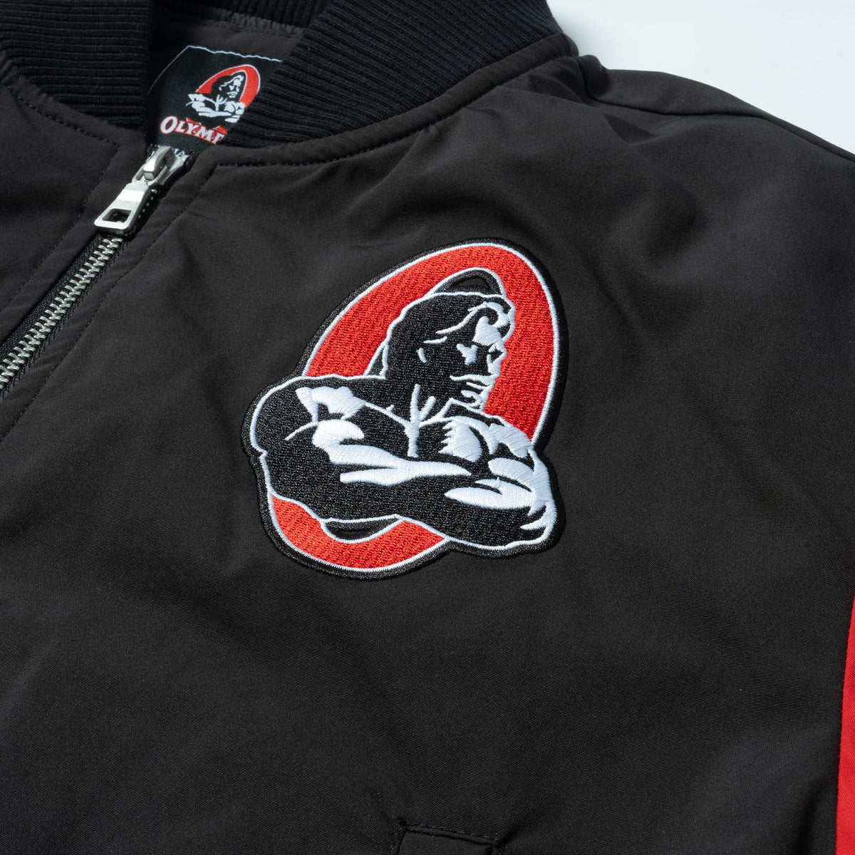 Signature Crop Bomber Jacket | Classic red and white Olympia bodybuilding logo on the left front chest