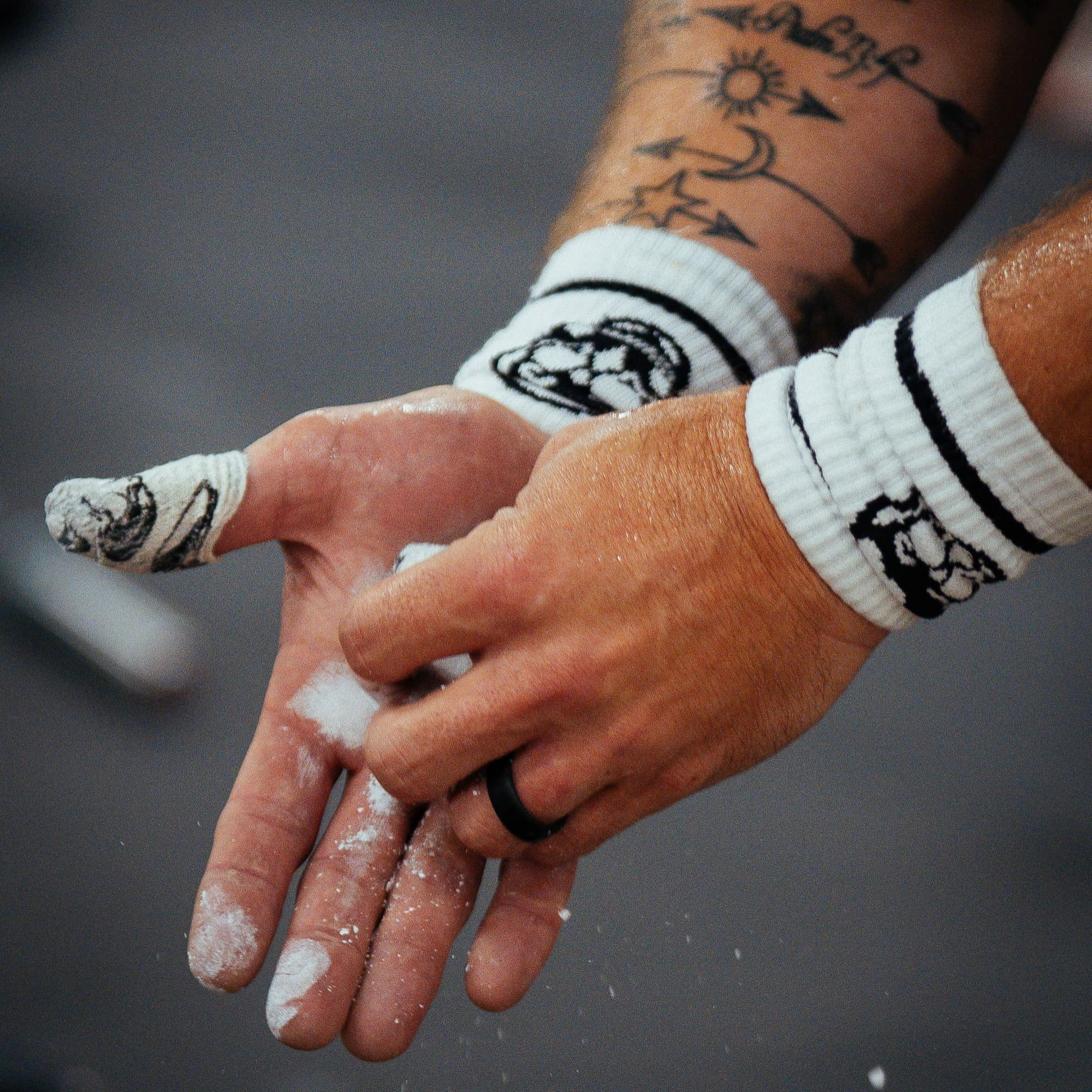 athlete applying chalk to hands with skull wrist bands on