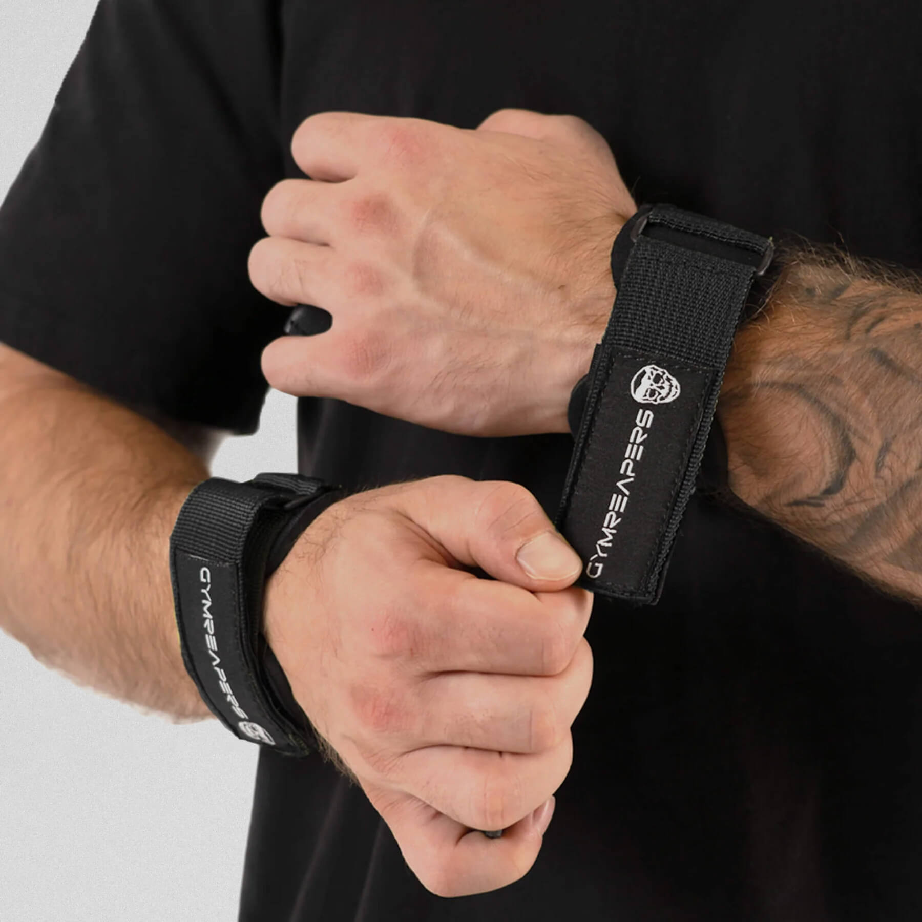 gymreapers athlete attaching grips onto wrist, while the other one has it on already.